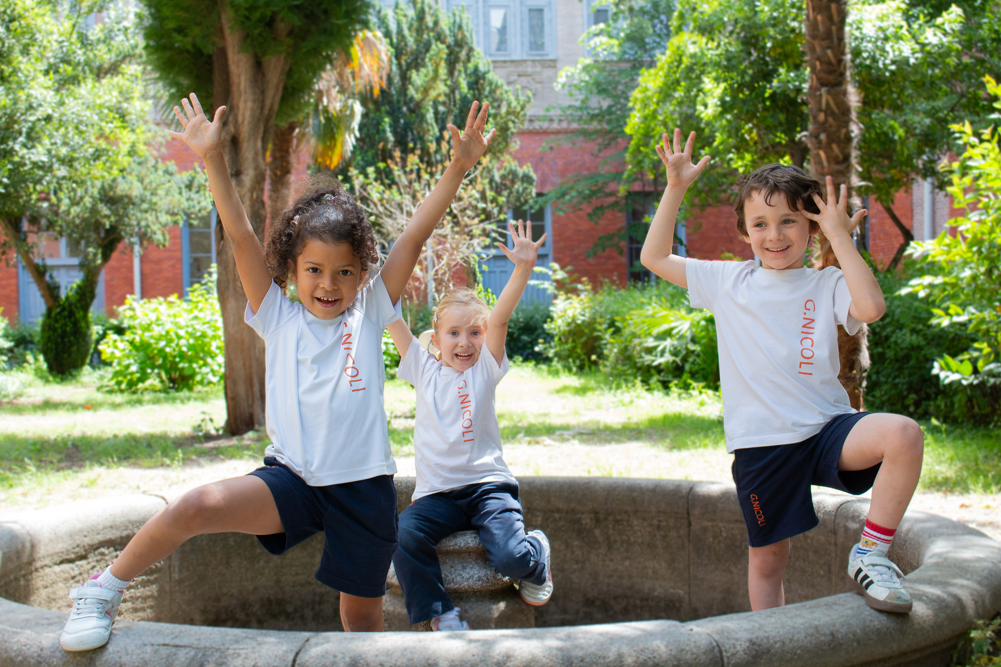 Tres niños de infantil en el patio interior con mucha vegetación del colegio internacional nicoli