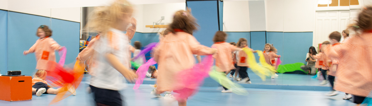 Niños bailando en clase de música con telas de colores