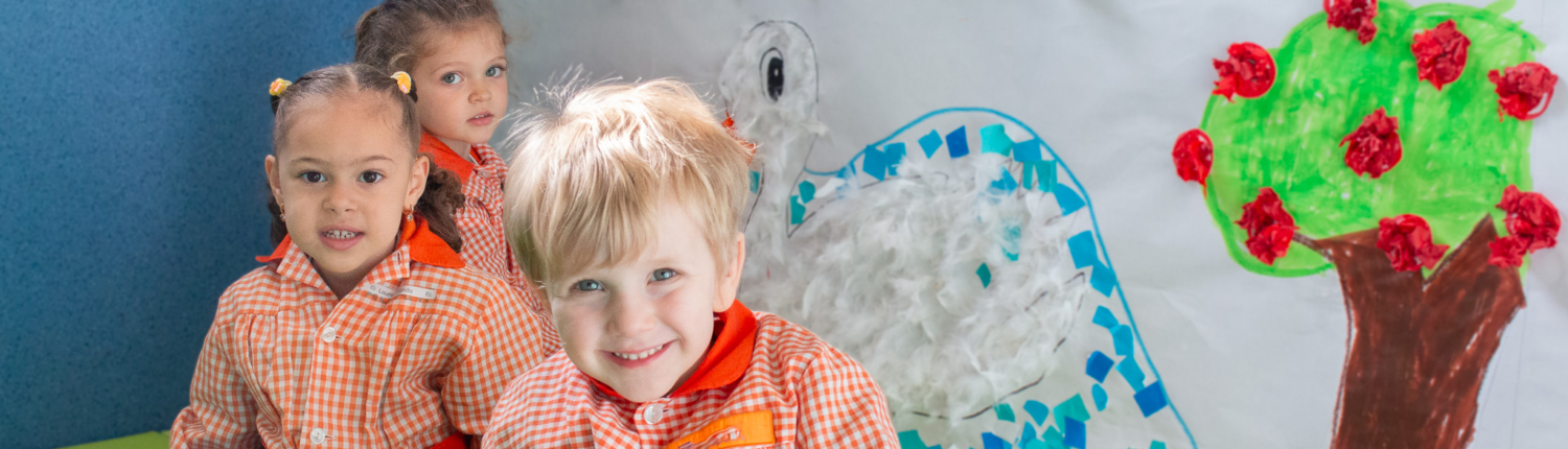 Niños muy sonrientes decorando un rincón de su clase de infantil