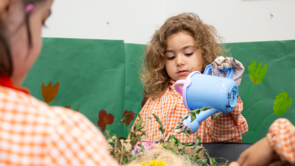 Niña en aula de infantil del colegio internacional nicoli regando plantas